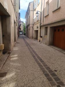 an empty street in an alley between two buildings at Grand Studio meublé chez COCO in Romans-sur-Isère +1 photo