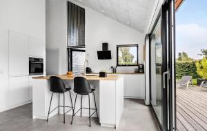 HejlsにあるCozy Home In Hejls With Saunaのカウンター付きのキッチン、バーのスツール2つ