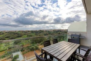 a balcony with a wooden table and chairs at Lovely home with beautiful view with communal pool by 360 Estates in Taʼ Bullara