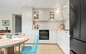 a kitchen with white cabinets and a table and a refrigerator at Cozy Home In Odder With Wifi in Odder +16 photos