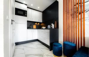 a kitchen with white cabinets and blue stools at 2 Bedroom Cozy Home In Sarbinowo in Sarbinowo