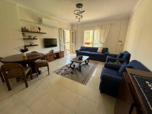 ein Wohnzimmer mit einem blauen Sofa und einem Tisch in der Unterkunft Charming Apartment 2 Bedroom In El Rehab in Burg el-Ḥudûd