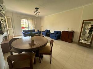 ein Wohnzimmer mit einem Tisch und blauen Stühlen in der Unterkunft Charming Apartment 2 Bedroom In El Rehab in Burg el-Ḥudûd