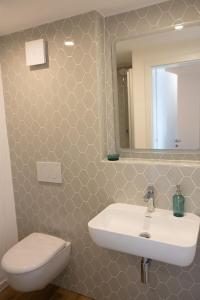 a bathroom with a sink and a toilet and a mirror at Küstenblick in Carolinensiel