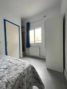 a white bedroom with a bed and a window at Beach apartment in Calafell +7 photos