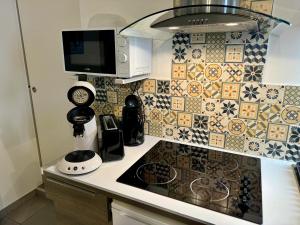 a kitchen with a stove top oven next to a tiled wall at La galerie du peintre in Saint-Laurent-de-la-Salanque