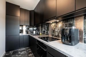a kitchen with black cabinets and a coffee maker on a counter at Black Luxury Apartment in Janów +16 photos