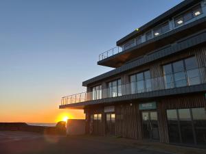 a building with the sunset in the background at Harbour Stays - The Marine Centre, Saundersfoot Harbour, SA69 9HE in Saundersfoot