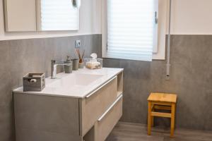 a bathroom with a white sink and a wooden stool at Casa Mirella in Cavallino-Treporti