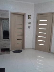 AngisaにあるGood Homeの白いタイルが敷かれた部屋にある2つの木製のドア