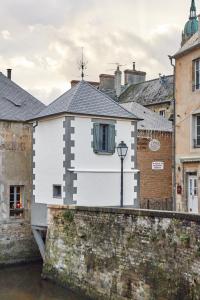 a white building on a wall next to a river at La Plus Petite Maison De France in Bayeux