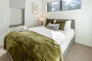 a bedroom with a large bed with a green blanket on it at Park and Stay 4BR Townhouse near Avon River in Linwood
