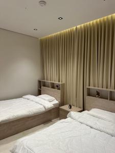two beds in a room with curtains at Layan residence in Al-Salam