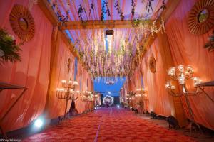 un couloir avec un lustre et un tapis rouge dans l'établissement hotel royal heritage, à Bharatpur