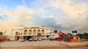 un grand bâtiment avec des voitures garées dans un parking dans l'établissement hotel royal heritage, à Bharatpur