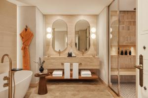 a bathroom with a tub and a sink and mirrors at Jumeirah Beach Hotel Dubai in Dubai