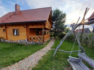 a log cabin with a red roof at Domki Mazury MAX in Rybical