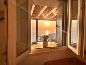 a window with a potted plant looking out at the sunset at Sunflower Tinos House in Istérnia