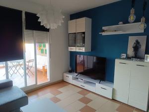 a living room with a television and a blue wall at Mirador de los Navegantes in Sanlúcar de Barrameda