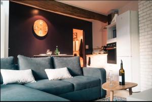 a blue couch in a living room with a clock on the wall at Le Cosy in Mâcon