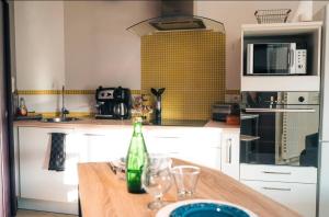 a kitchen with a table with glasses and a bottle at Le Cosy in Mâcon