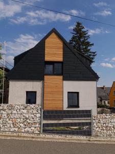 a house with a black roof and a stone wall at Ferienhaus Anton Günther in Bernsbach