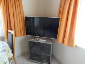 a flat screen tv on a wall with orange curtains at Apartment Beck in Wilderswil