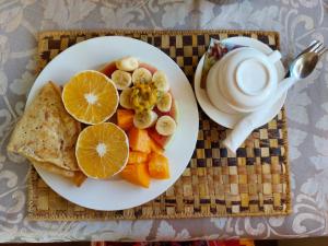 a plate of food with fruit and a cup of coffee at Stonefish Inn Jambiani in Jambiani