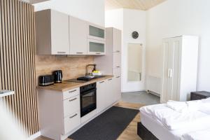 a kitchen with white cabinets and a bed in a room at KMS Homes - air conditioning - near Legoland Günzburg in Bubesheim +23 photos