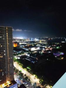 a view of a city at night with a tall building at Breeze Residences Manila in Manila