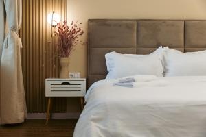 a bedroom with a large white bed and a side table at Epic Boutique in Sibiu