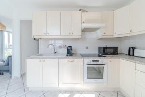 a white kitchen with white cabinets and a sink at Spacious Apartment for 8 People - Bron Grand Clement in Bron