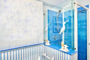 a blue tiled bathroom with two white birds in a shower at Villa sul mare a Capri - Panorama Mozzafiato in Anacapri +46 photos
