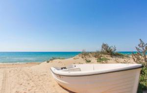 ein weißes Boot auf dem Sand am Strand in der Unterkunft Cozy Apartment In Marina Di Modica in Marina di Modica