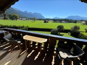 a deck with chairs and a table and a view of a field at Ferienwohnungen Alpinum in Krün