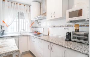 a white kitchen with white cabinets and a microwave at 2 Bedroom Amazing Apartment In Chipiona in Chipiona