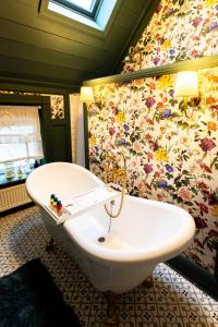 a bathroom with a white tub and a floral wallpaper at Wohnen im Carl Maria von Weber Geburtshaus in Eutin