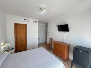 a bedroom with a bed and a dresser and a television at Hostal el Ancla in Alcalá del Río