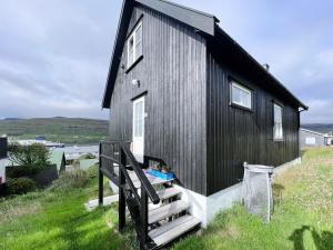 a black house with a staircase leading up to it at Charming 3-bedroom Home With Stunning Fjord Views in Tvøroyri