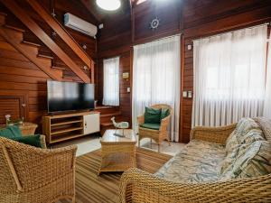 a living room with a television and wicker furniture at Casa c/ piscina privativa a 150m da praia PU9263 in Itajubá