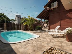 a swimming pool in a yard with chairs and a house at Casa c/ piscina privativa a 150m da praia PU9263 in Itajubá