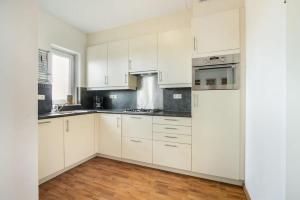 a white kitchen with white cabinets and a window at Hello Zeeland - Appartement Port Scaldis 19-031 in Breskens