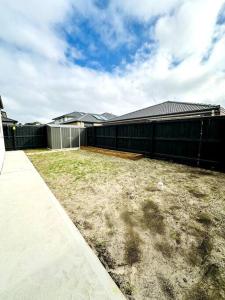 a black building with a fence and a yard at Family retreat-Spacious 4BR in Donnybrook