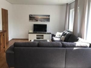 a living room with a couch and a flat screen tv at Hello Zeeland - Vakantiehuis Het Heem 39 in Breskens