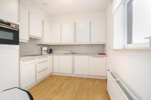 a white kitchen with white cabinets and a wooden floor at Hello Zeeland - Appartement Port Scaldis 13-112 in Breskens