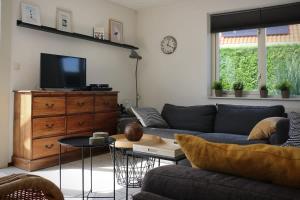 a living room with a couch and a tv at Hello Zeeland - Vakantiehuis Schelde 148 in Breskens +4 photos