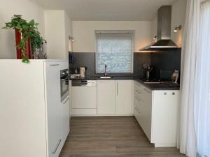 a kitchen with white cabinets and a window at Hello Zeeland - Vakantiehuis Zwin 182 in Breskens