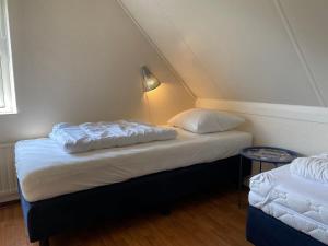 a bedroom with two beds and a lamp in a attic at Hello Zeeland - Vakantiehuis Zwin 182 in Breskens +11 photos