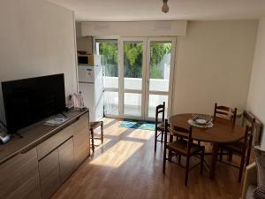 ein Wohnzimmer mit einem Esstisch und einem TV in der Unterkunft Appartement proche Bordeaux et Aéroport in Mérignac