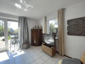 a living room with a flat screen tv and windows at Hello Zeeland - Vakantiehuis Zwin 092 in Breskens